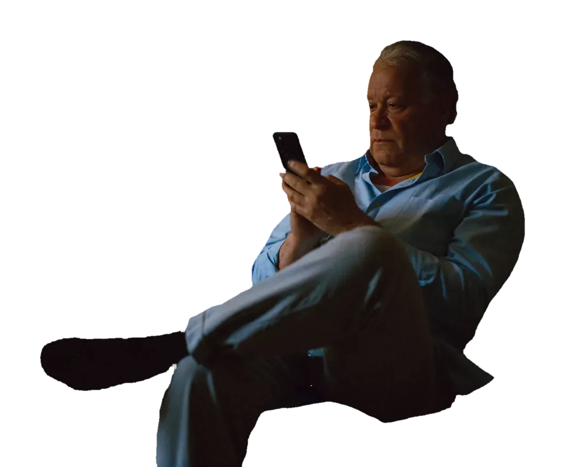 Mann i sofaen om kvelden med mobilen